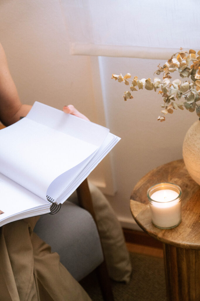 Cuaderno abierto junto a una vela y flores